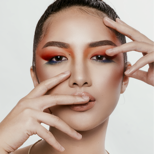 Eine Frau mit leuchtend orange-blauem Make-up im Gesicht.